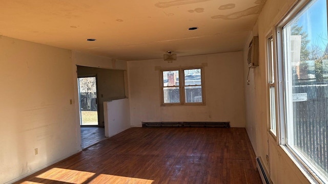 spare room featuring dark hardwood / wood-style flooring, an AC wall unit, and a baseboard heating unit