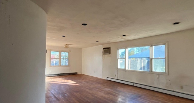 empty room with hardwood / wood-style floors, plenty of natural light, and a baseboard heating unit