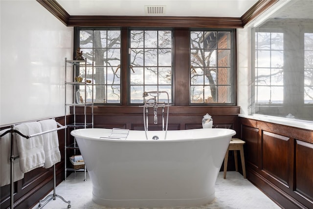 bathroom with plenty of natural light, crown molding, and a washtub