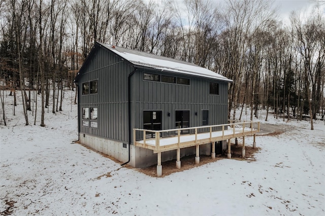 snow covered rear of property with a deck