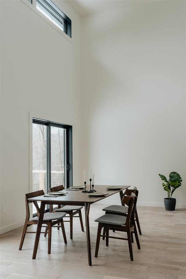 dining room featuring a high ceiling and light hardwood / wood-style flooring