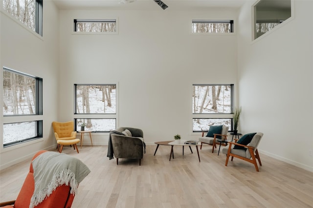 living area with a towering ceiling and light hardwood / wood-style flooring