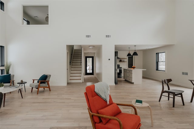 living room featuring light wood-type flooring and a high ceiling