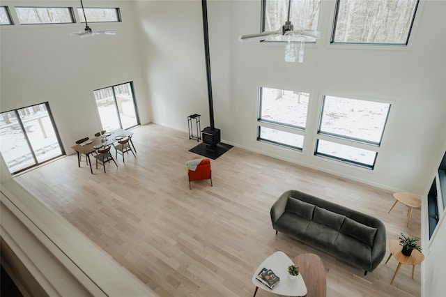 living room featuring a wealth of natural light, light wood-type flooring, a wood stove, and ceiling fan