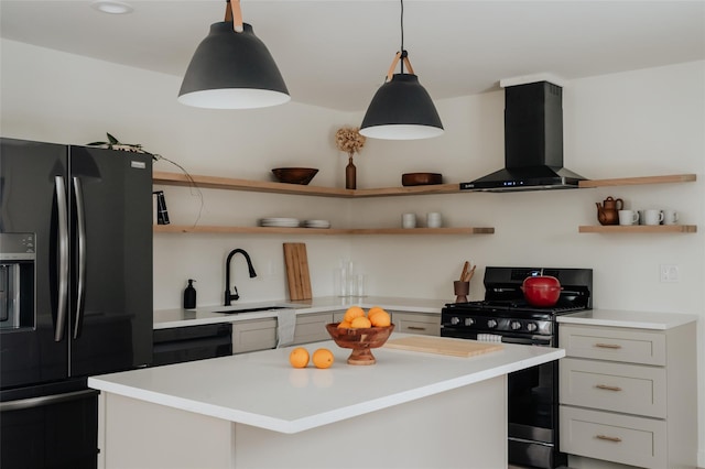 kitchen featuring pendant lighting, black appliances, wall chimney range hood, sink, and a kitchen island