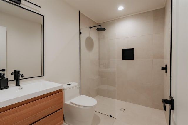 bathroom featuring a tile shower, vanity, toilet, and tile patterned floors