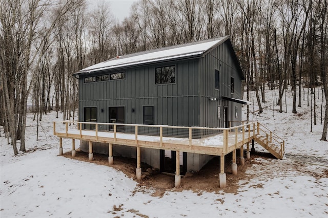 snow covered rear of property with a wooden deck