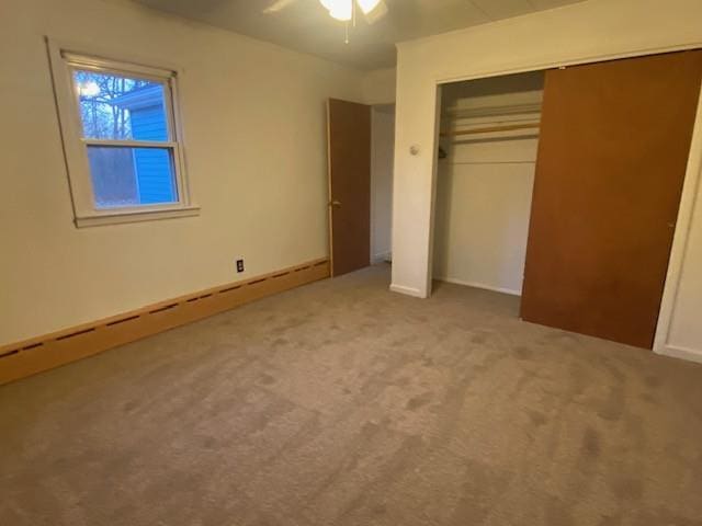 unfurnished bedroom with carpet, a closet, and a baseboard heating unit