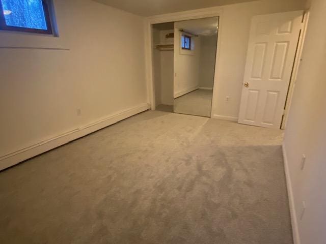 basement with baseboard heating and light colored carpet