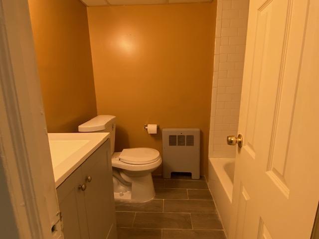 bathroom with radiator heating unit, tile patterned flooring, a bath, toilet, and vanity