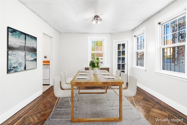 dining space with dark parquet flooring and a textured ceiling