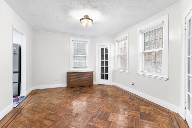 unfurnished dining area with dark parquet flooring, a textured ceiling, and french doors