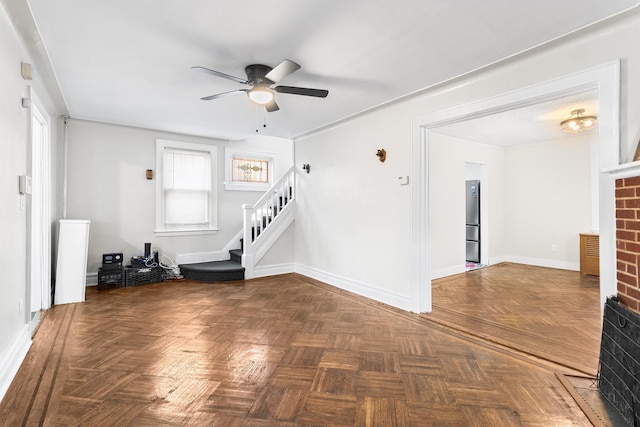 unfurnished living room with ceiling fan and dark parquet floors