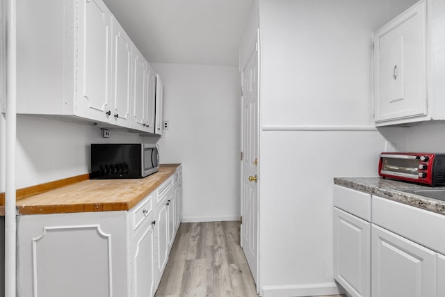 kitchen with white cabinets, light hardwood / wood-style floors, and butcher block countertops