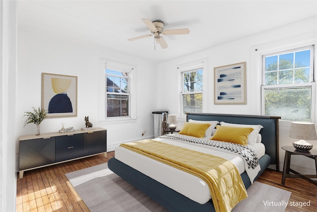 bedroom featuring dark hardwood / wood-style floors, ceiling fan, and multiple windows