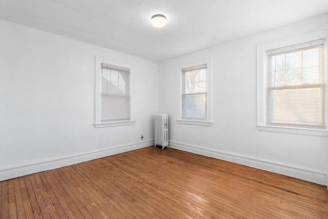 empty room featuring radiator heating unit and hardwood / wood-style floors