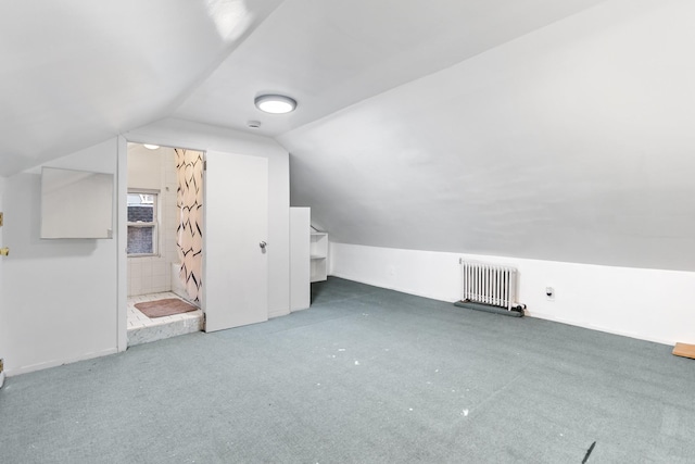 additional living space with carpet flooring, radiator, and vaulted ceiling