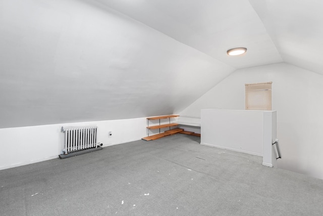 additional living space with carpet, radiator heating unit, and vaulted ceiling