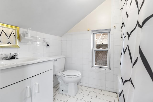 full bathroom featuring vanity, vaulted ceiling, tile patterned floors, and tile walls