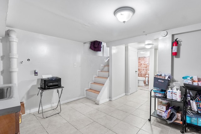 basement featuring sink and light tile patterned floors