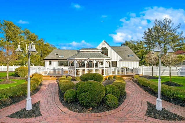 rear view of house featuring a fenced front yard and roof with shingles