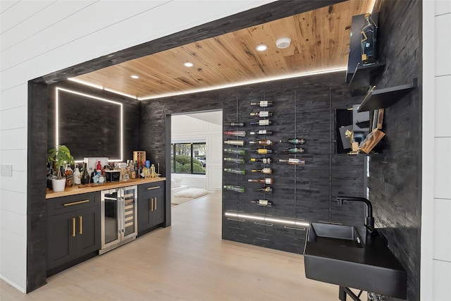 wine room featuring wooden ceiling, indoor bar, light hardwood / wood-style floors, and beverage cooler