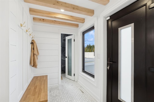 mudroom featuring wood walls, beam ceiling, and light tile patterned flooring