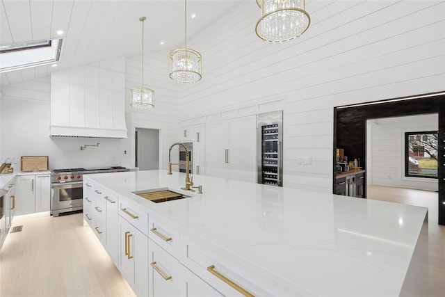 kitchen featuring designer stove, white cabinets, hanging light fixtures, and high vaulted ceiling