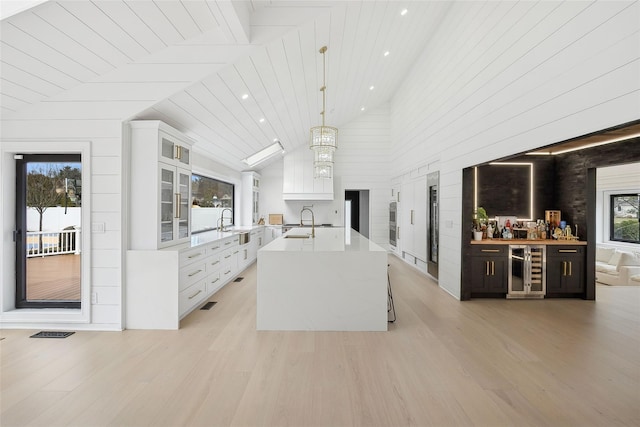 living room with sink, light hardwood / wood-style flooring, wood ceiling, high vaulted ceiling, and beverage cooler