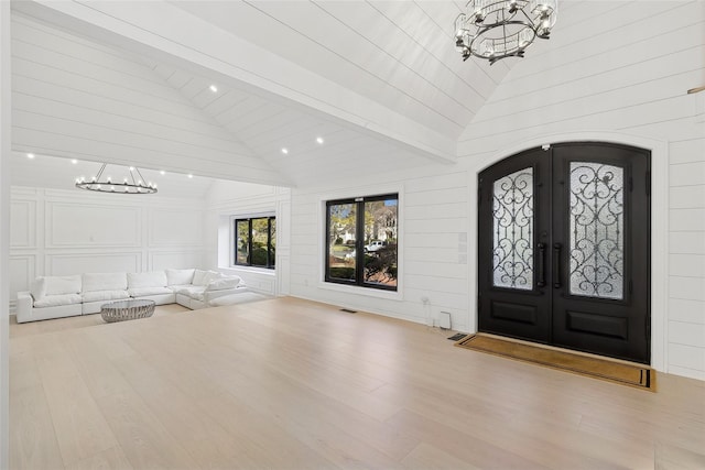foyer with wood finished floors, beam ceiling, french doors, and an inviting chandelier