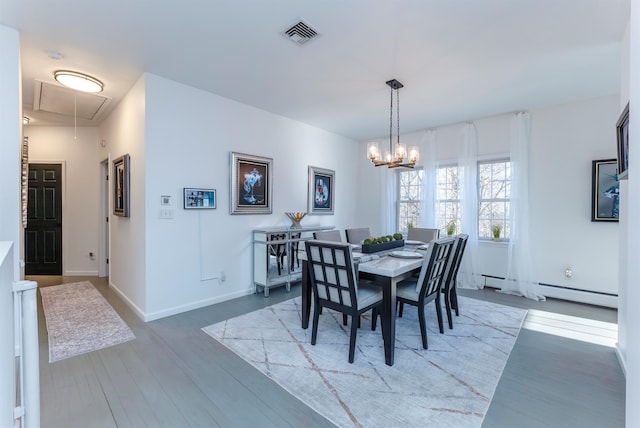 dining area with hardwood / wood-style floors, a baseboard radiator, and a notable chandelier