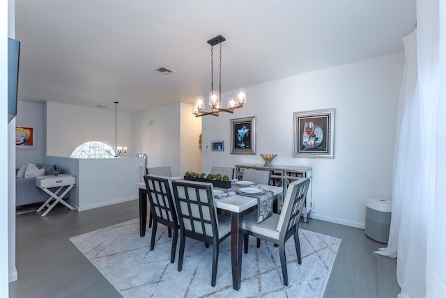 dining area with dark wood-type flooring and a notable chandelier