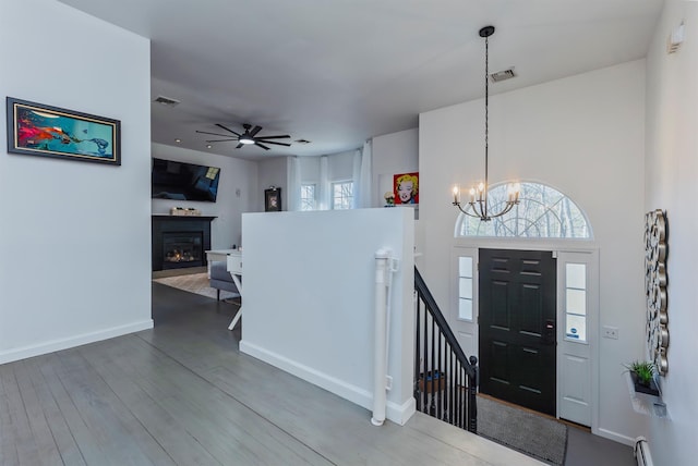 entryway featuring hardwood / wood-style flooring, ceiling fan with notable chandelier, a towering ceiling, and baseboard heating