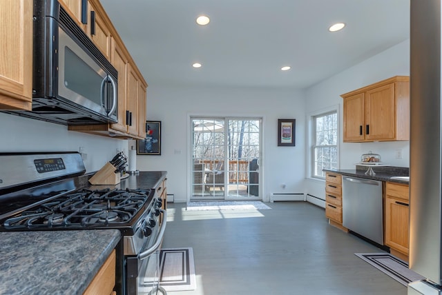 kitchen featuring dark stone counters, stainless steel appliances, a baseboard radiator, and dark wood-type flooring