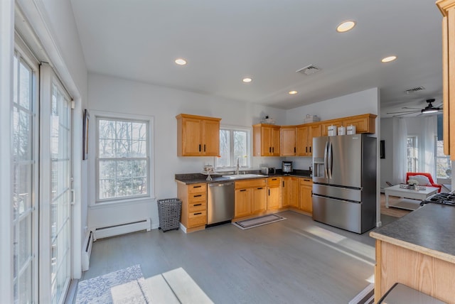 kitchen with light wood-type flooring, stainless steel appliances, a baseboard radiator, and plenty of natural light