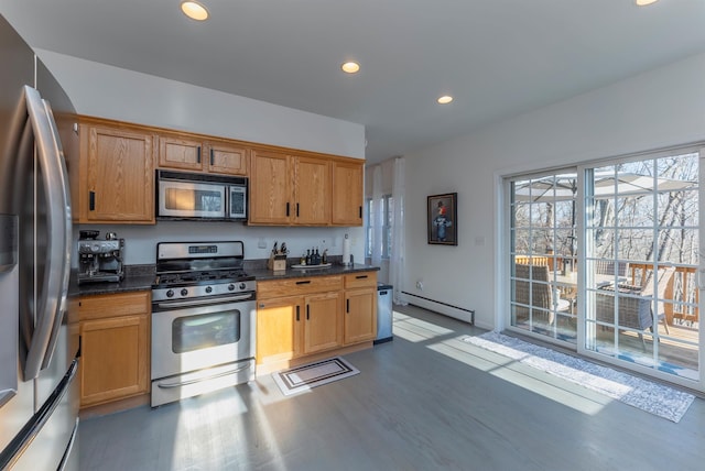 kitchen featuring appliances with stainless steel finishes, a baseboard radiator, dark stone countertops, and wood-type flooring