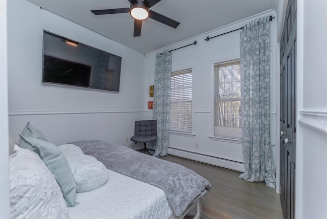 bedroom with wood-type flooring, baseboard heating, crown molding, and ceiling fan