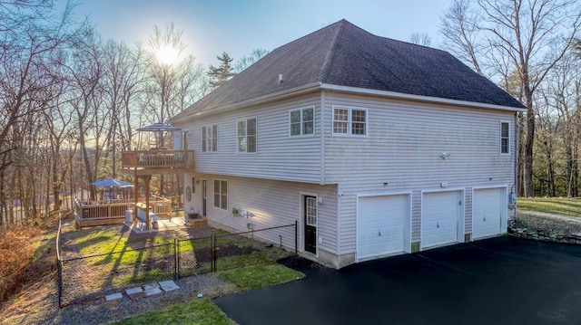 property exterior at dusk with a garage and a wooden deck