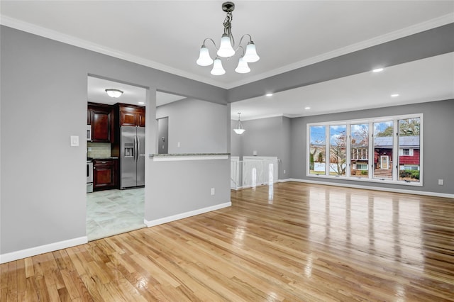 unfurnished living room with a chandelier, light hardwood / wood-style flooring, and crown molding