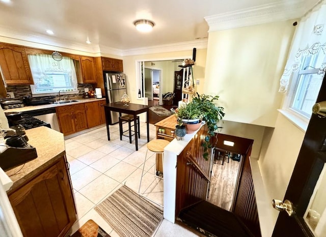 kitchen with stainless steel fridge, tasteful backsplash, ornamental molding, sink, and light tile patterned floors