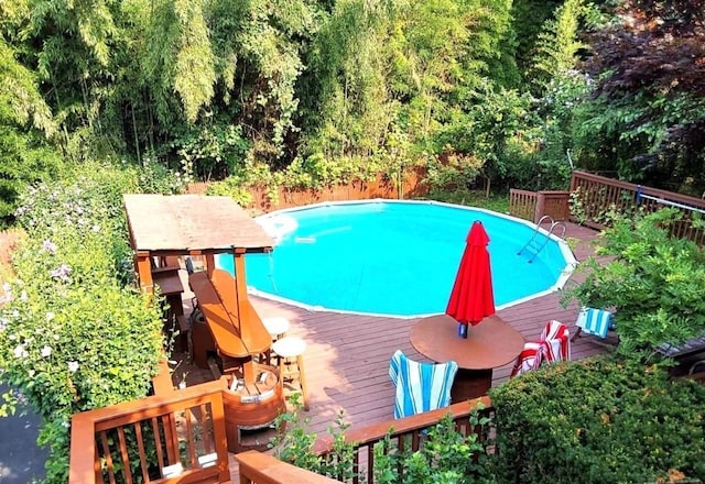 outdoor pool with a deck and a forest view