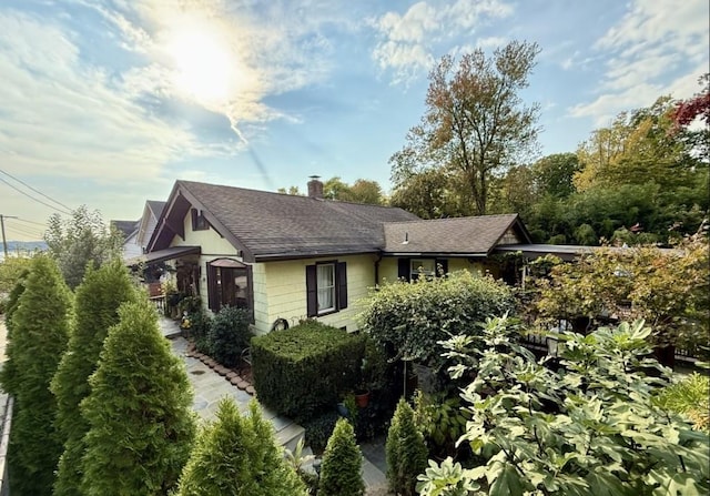 view of side of home with a shingled roof and a chimney
