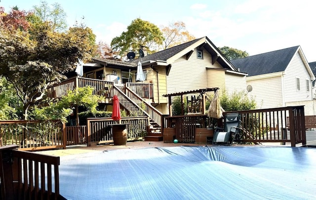 rear view of property featuring a wooden deck, a covered pool, and stairway