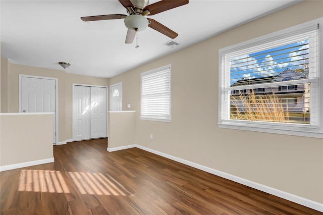 unfurnished bedroom with ceiling fan, dark hardwood / wood-style floors, and multiple windows