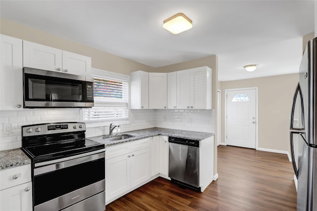 kitchen with appliances with stainless steel finishes, dark hardwood / wood-style floors, white cabinetry, and light stone counters