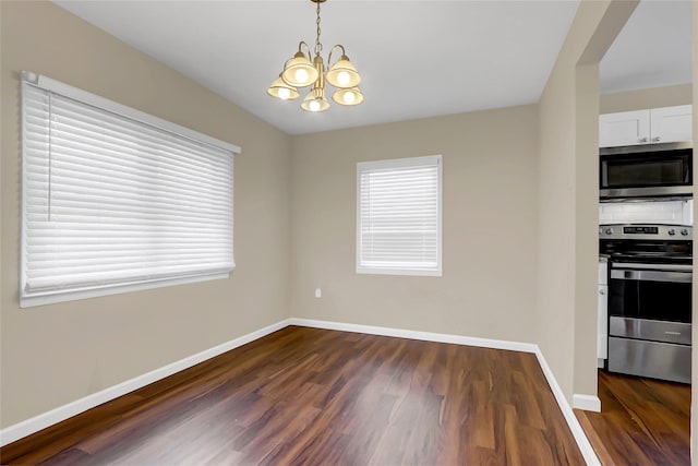 interior space with dark wood-type flooring, a wealth of natural light, and a chandelier