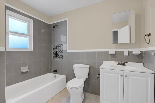 full bathroom featuring tile patterned floors, vanity, tiled shower / bath combo, tile walls, and toilet