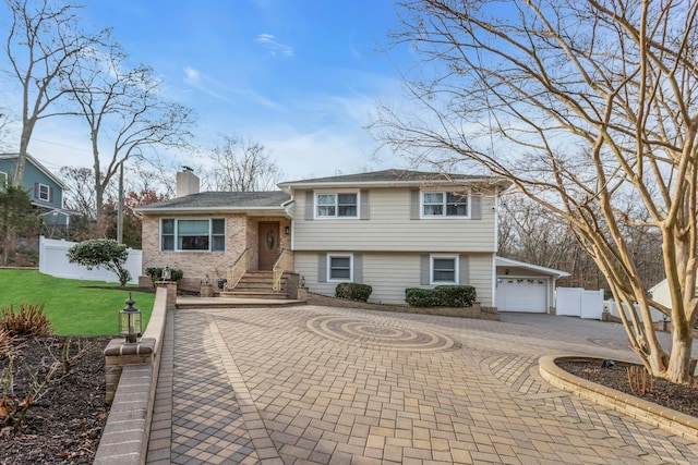 tri-level home featuring a garage and a front lawn