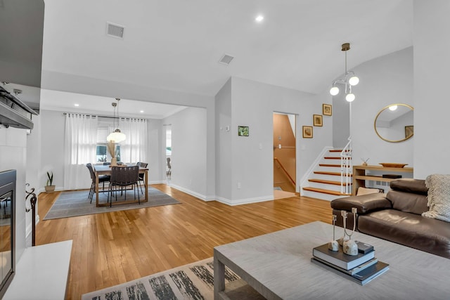 living room featuring hardwood / wood-style floors, vaulted ceiling, and an inviting chandelier