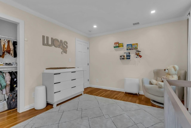 sitting room with light hardwood / wood-style floors and crown molding